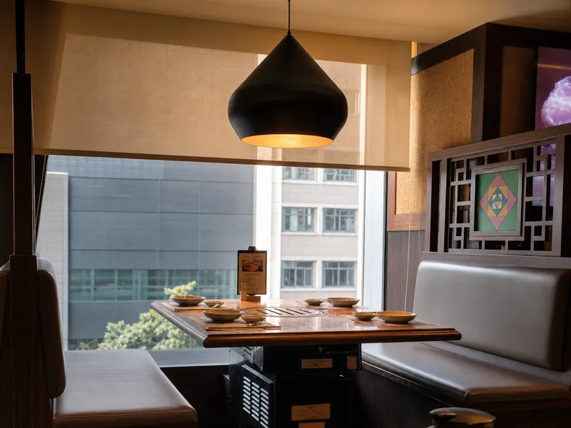 Window booth with a built-in grill and pendant lamp, overlooking Hong Kong high-rises